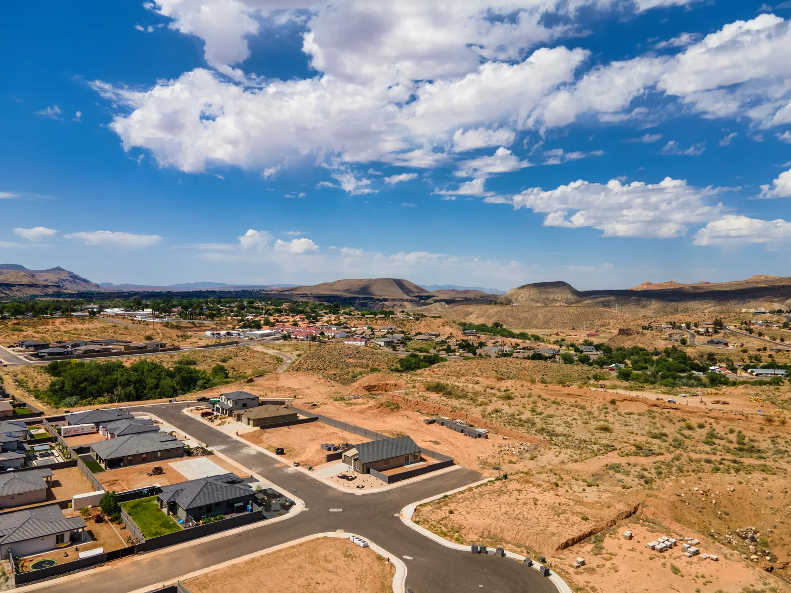 Aerial view of new La Verkin homes with cliffs and a green valley beyond