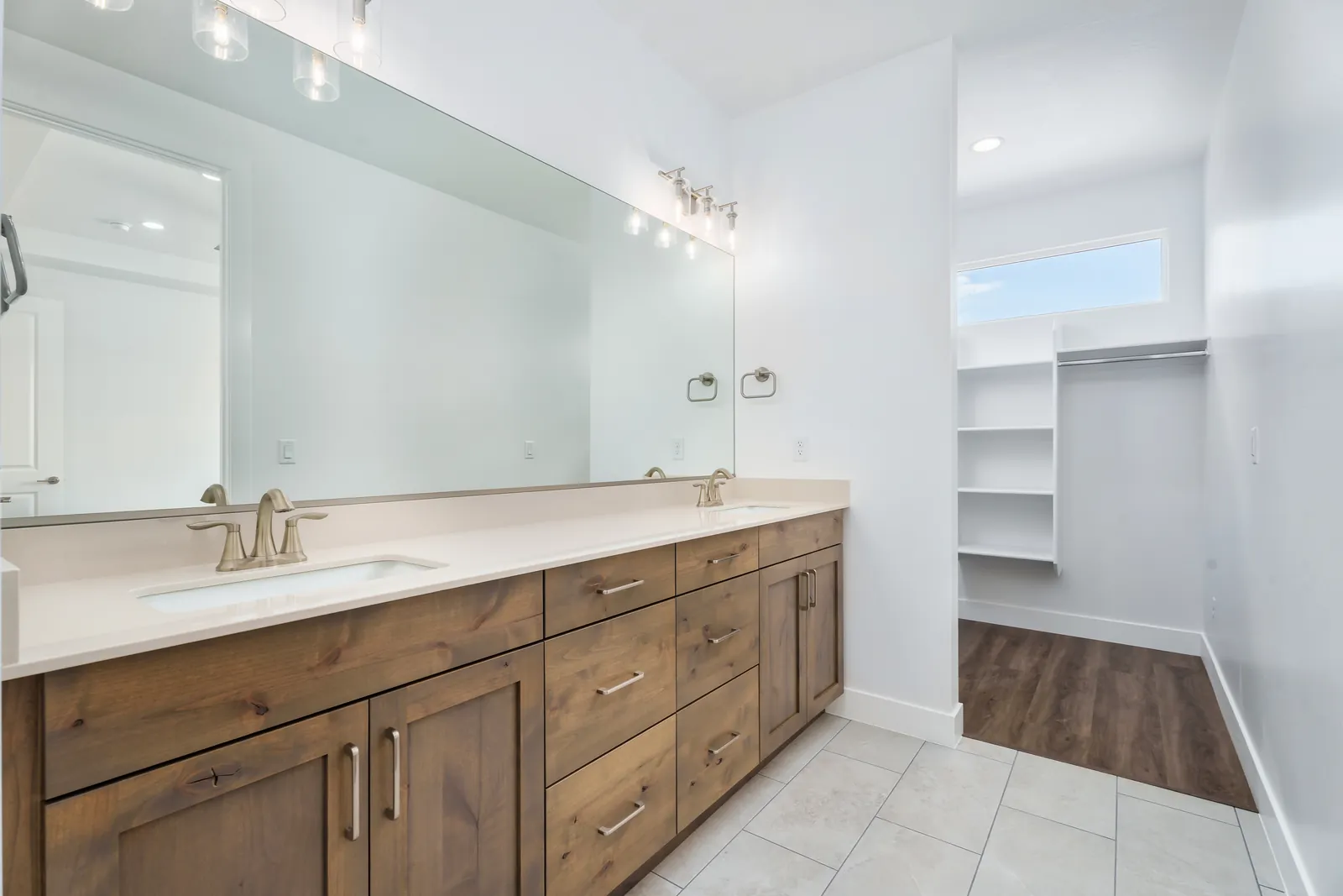 Double vanity with wood cabinets and a walk-in closet