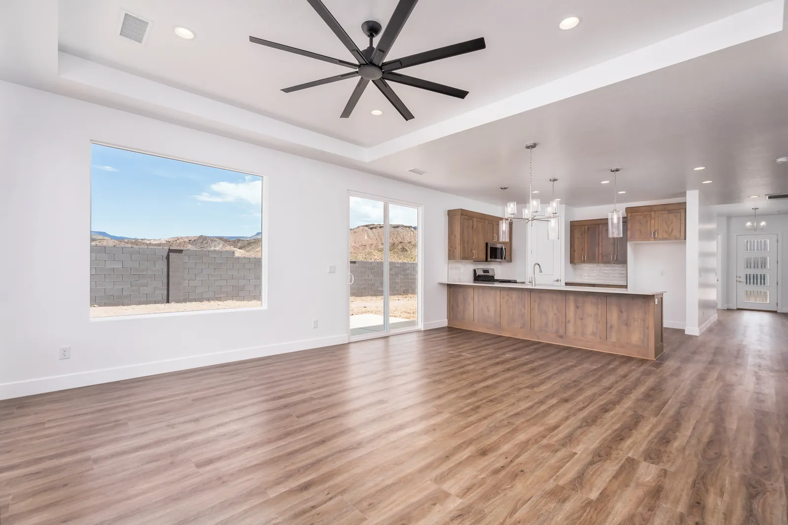 Great room with a large black ceiling fan and a row of windows