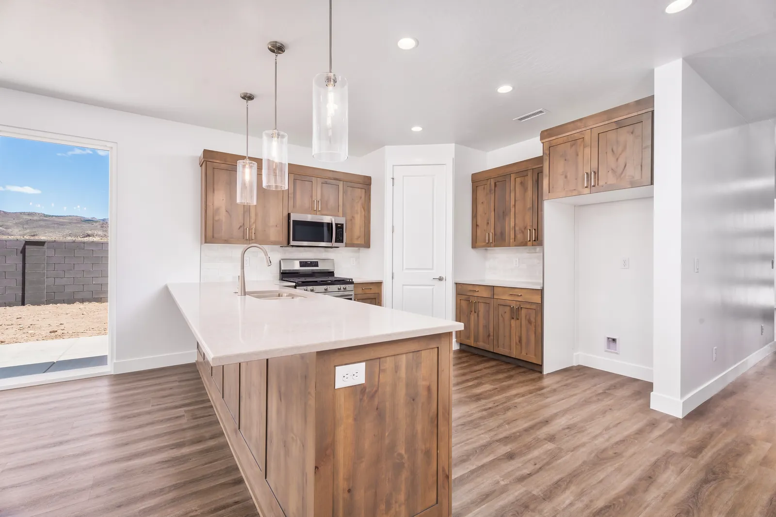 Kitchen with wood cabinets, a long island and pendant lights