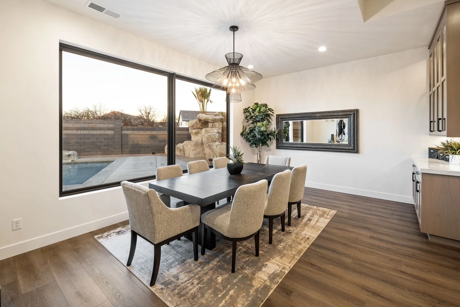 Dining table under a pendant light, beside a big window