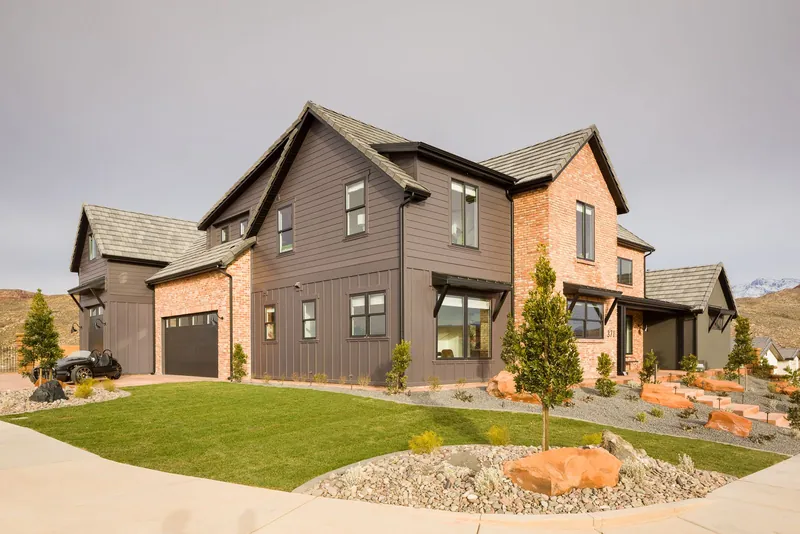 Two-story farmhouse-style home with a lawn and landscaping