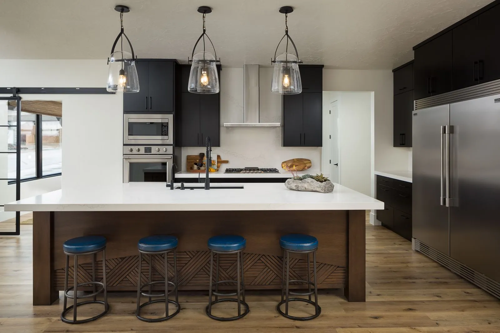 Kitchen island with blue stools under three pendant lights