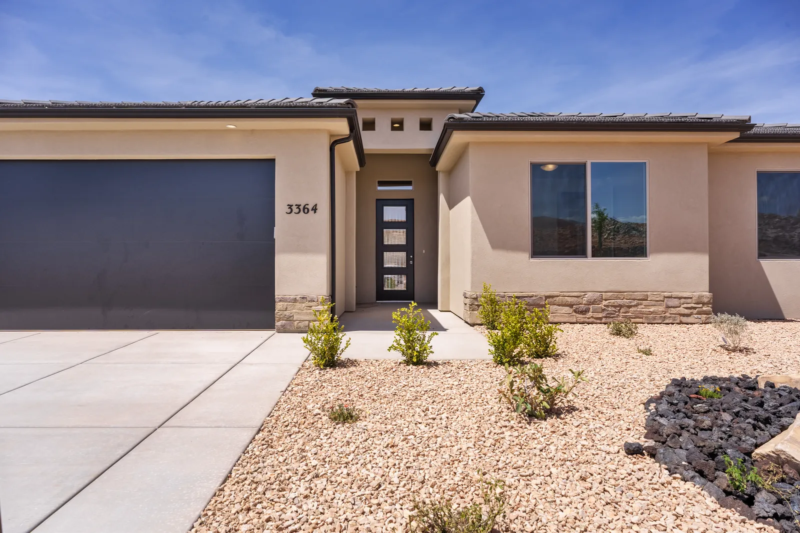 Front of a single-story home with a dark garage door and a stone accent
