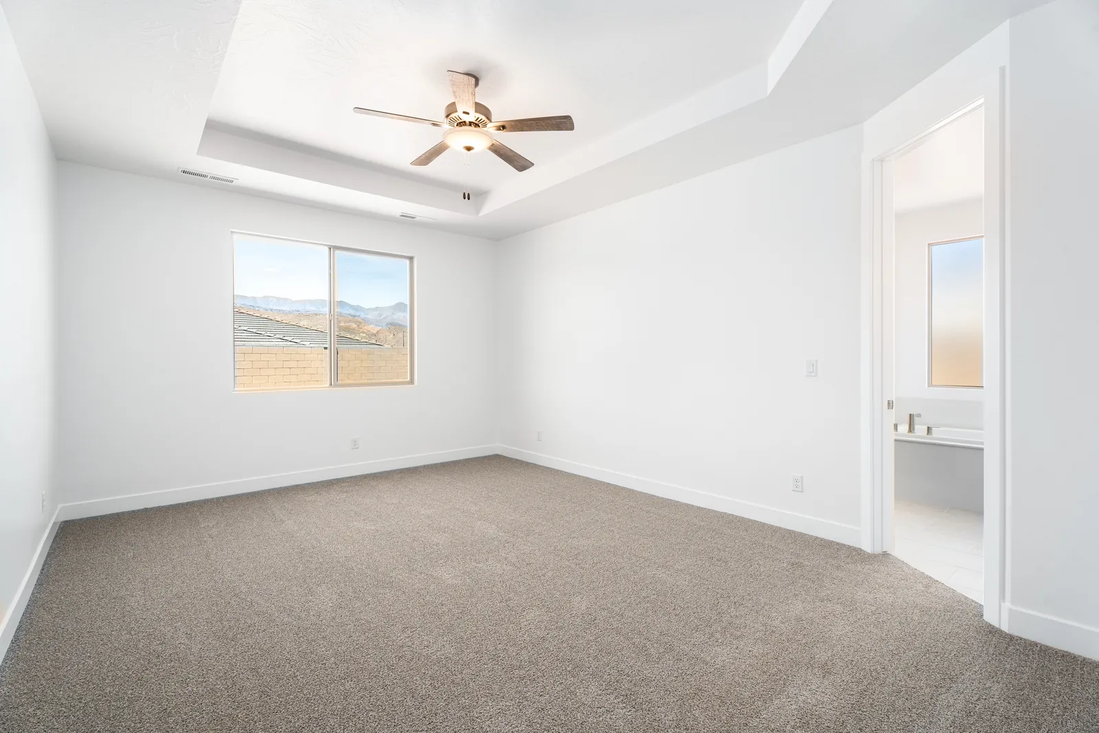 Primary bedroom with a tray ceiling and a window