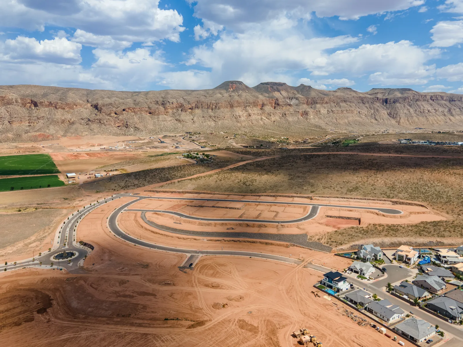 Aerial view of new lots with green fields and cliffs in the distance