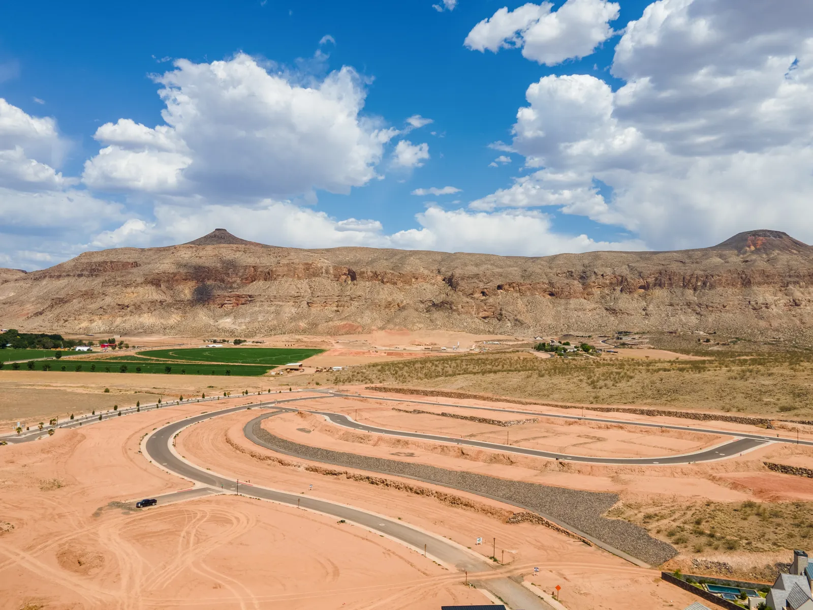 Aerial view of new streets on red earth with a mesa and clouds beyond
