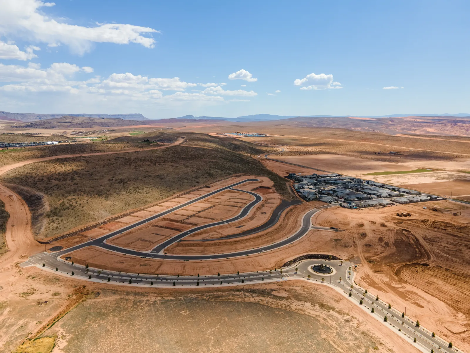 Wide aerial view of a new subdivision's road loops on red ground