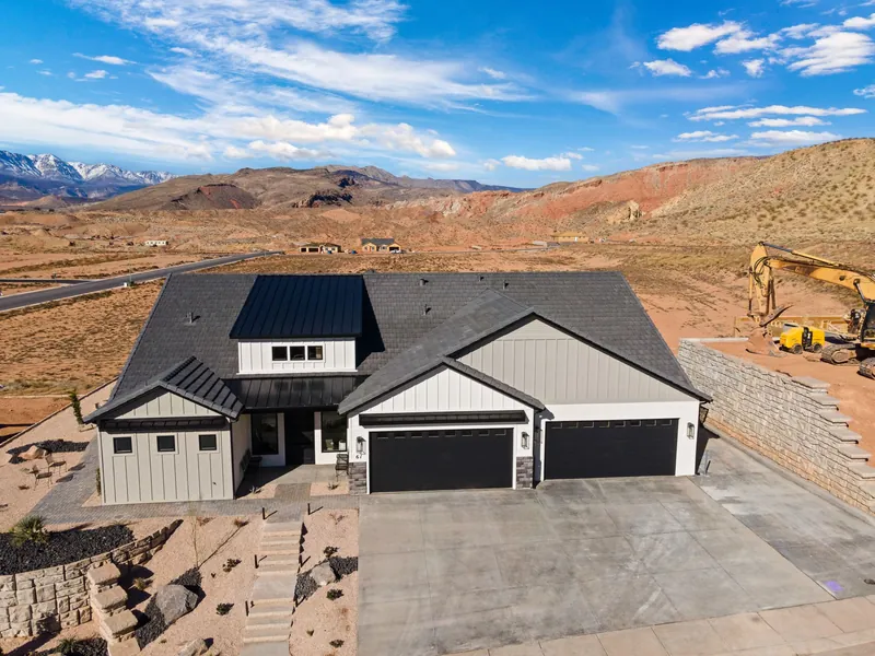 Aerial view of a home with board-and-batten gables and two garage doors