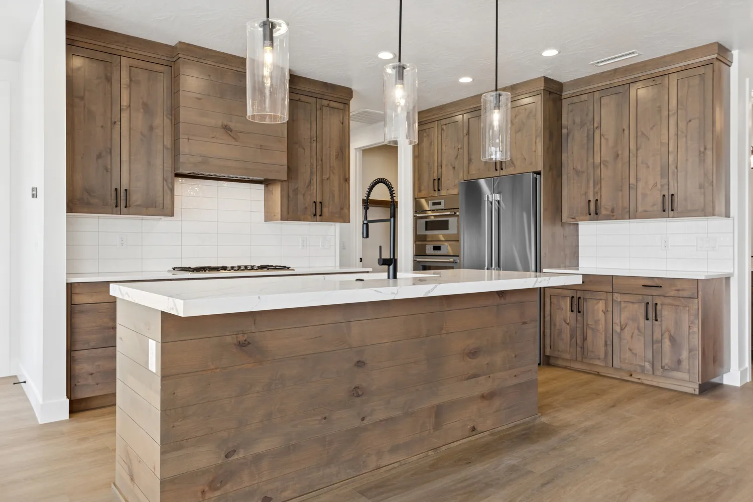 Kitchen with light wood cabinets and glass pendants