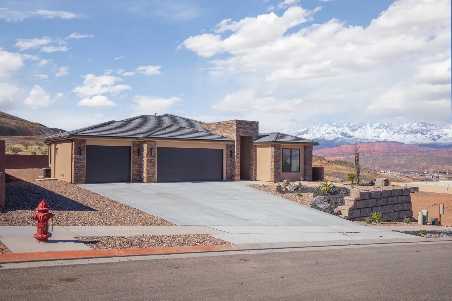 Single-story home with two garage doors and snow on the mountains behind