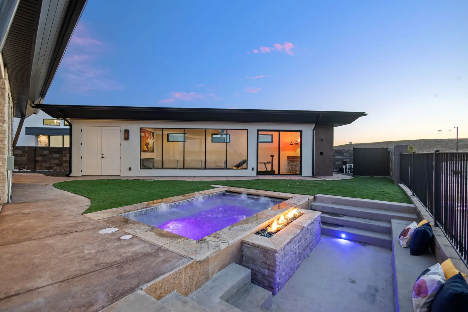 Backyard with a spa and a fire feature at dusk