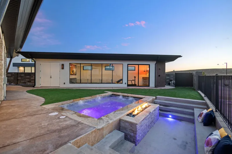 Backyard with a spa and a fire feature at dusk