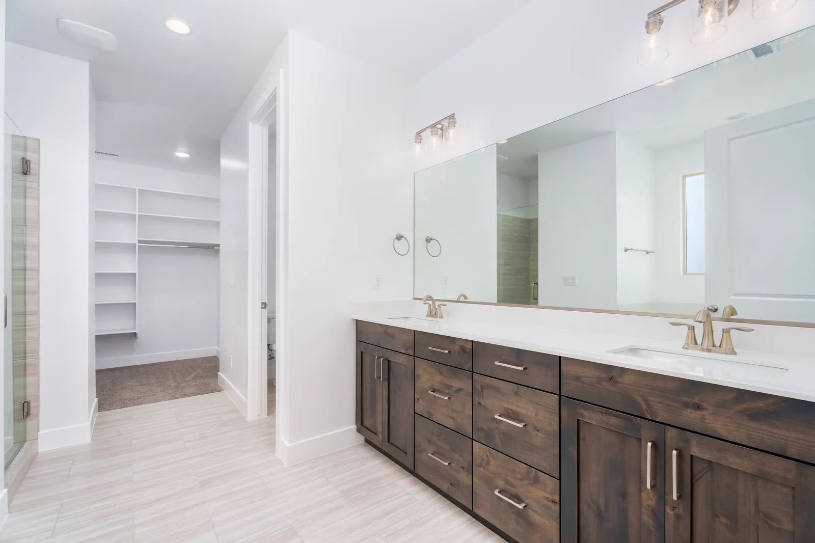 Primary bathroom with a double vanity and a walk-in closet beyond