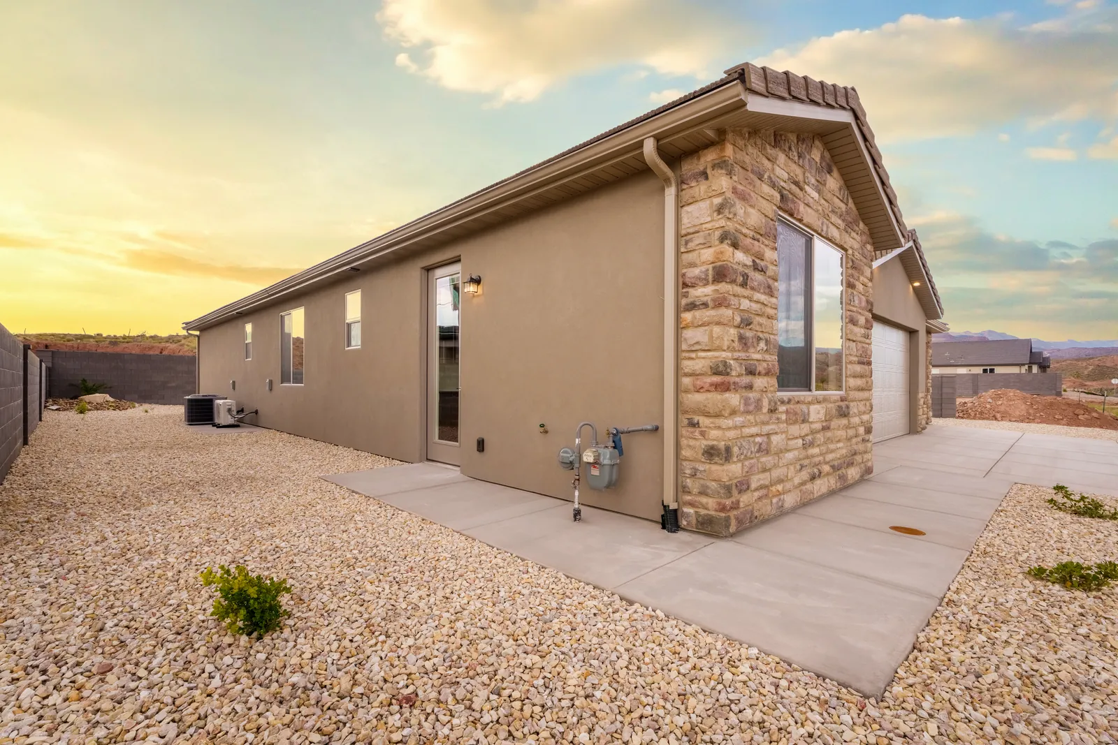 Side view of a stone-accented home under a sunset sky