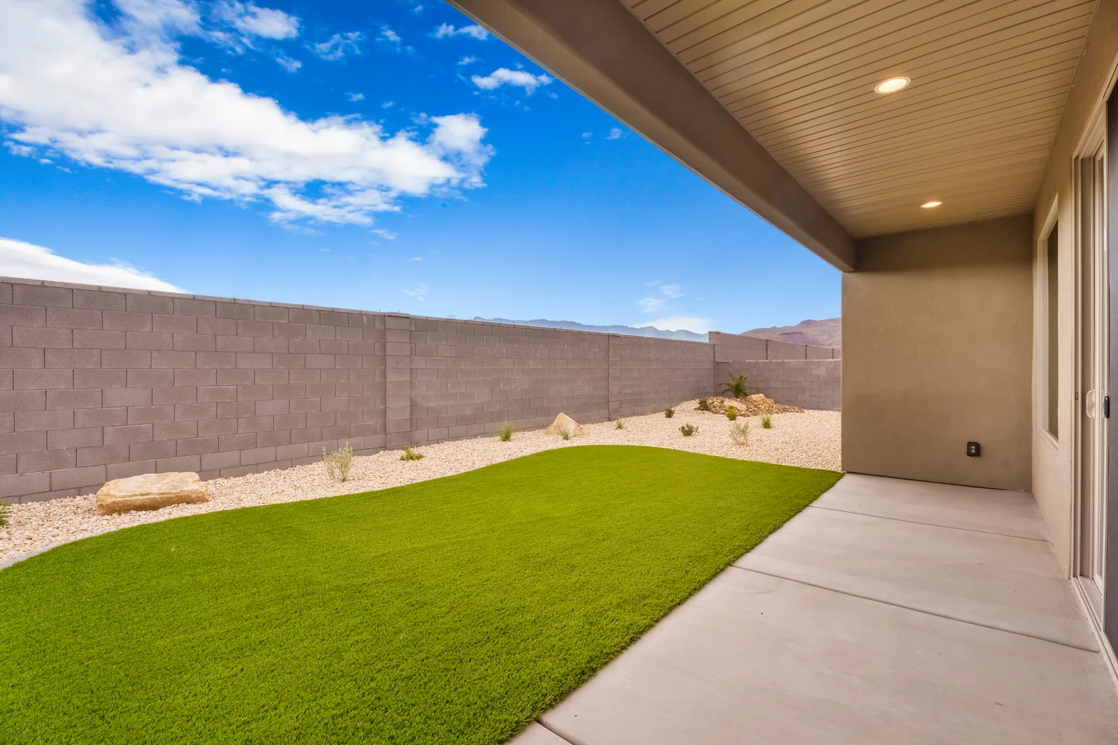 Covered patio looking onto a green backyard lawn