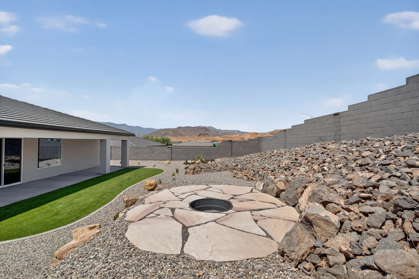 Backyard with a stone fire pit, lawn and landscaped rock beds
