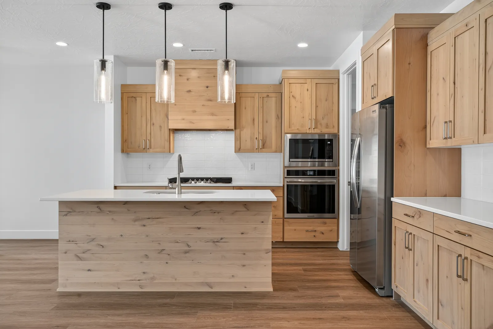 Kitchen with light wood cabinets, an island and three pendant lights
