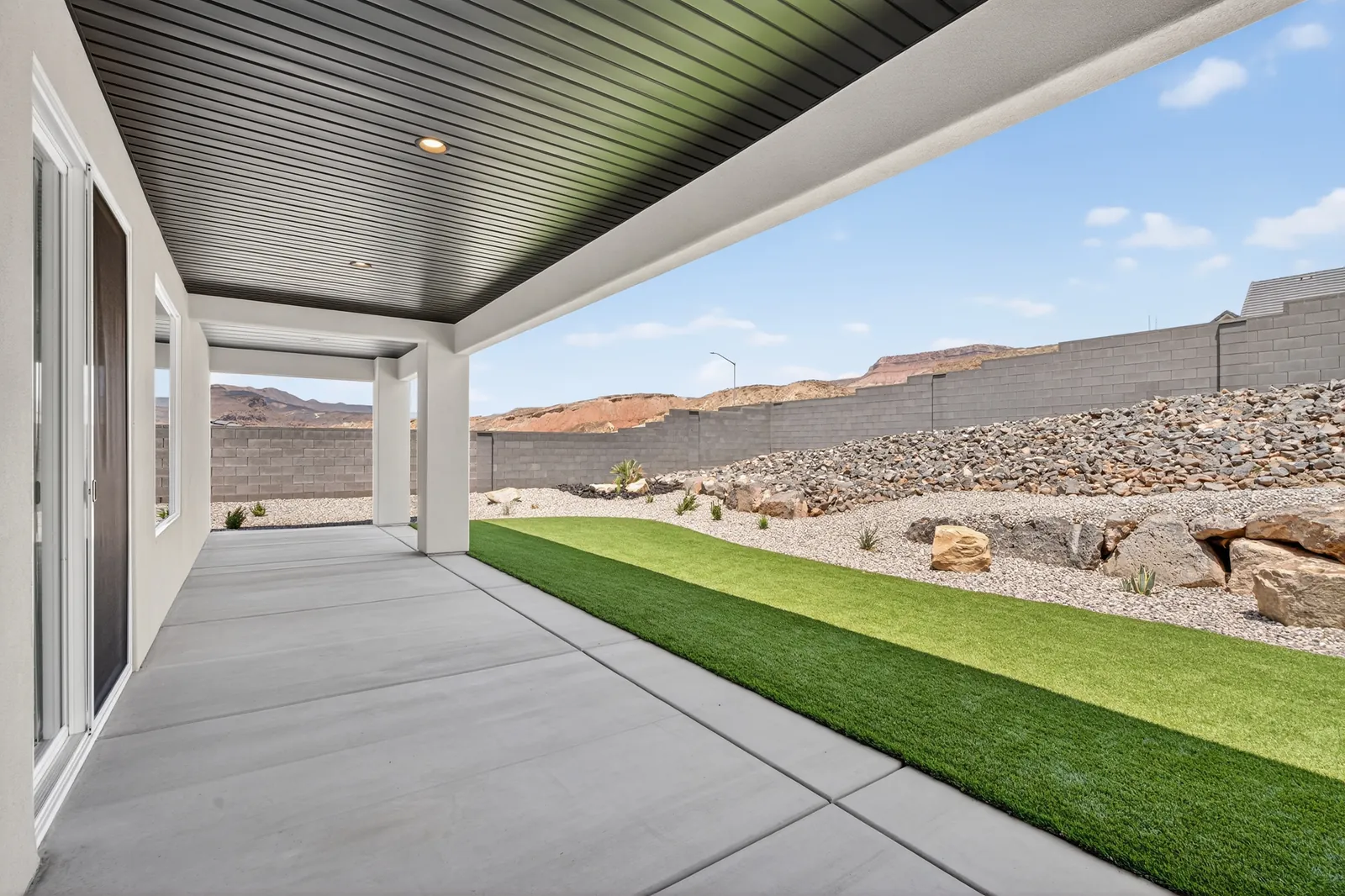 Covered patio and a strip of lawn along the back wall