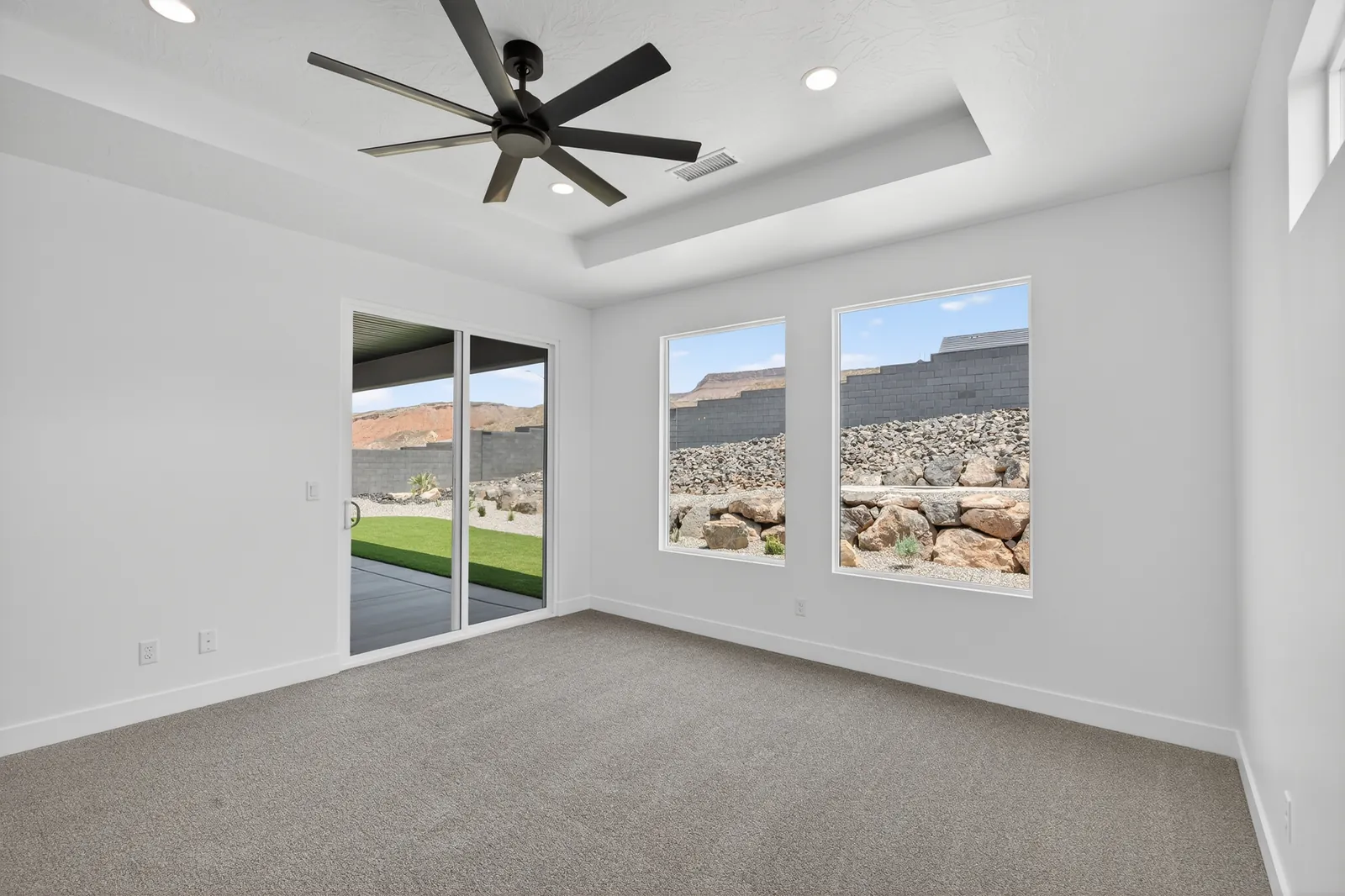 Primary bedroom with a ceiling fan and sliding door to the patio
