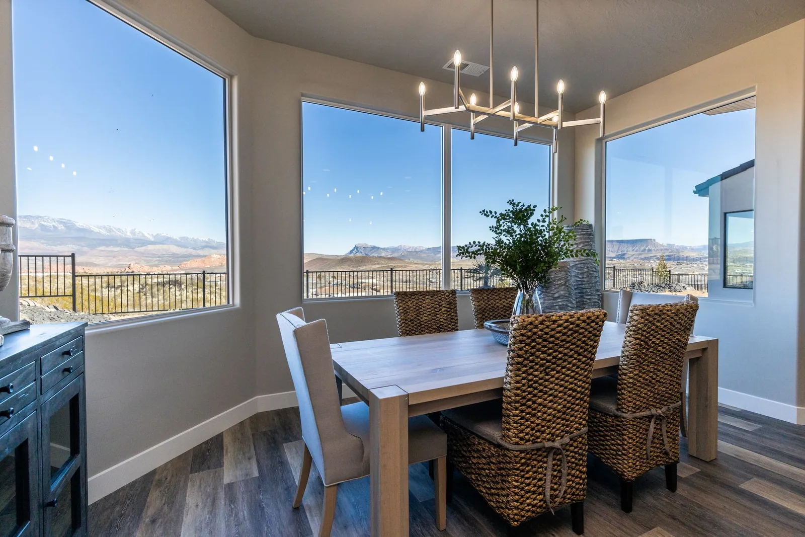 Dining table under a chandelier, with windows on two sides