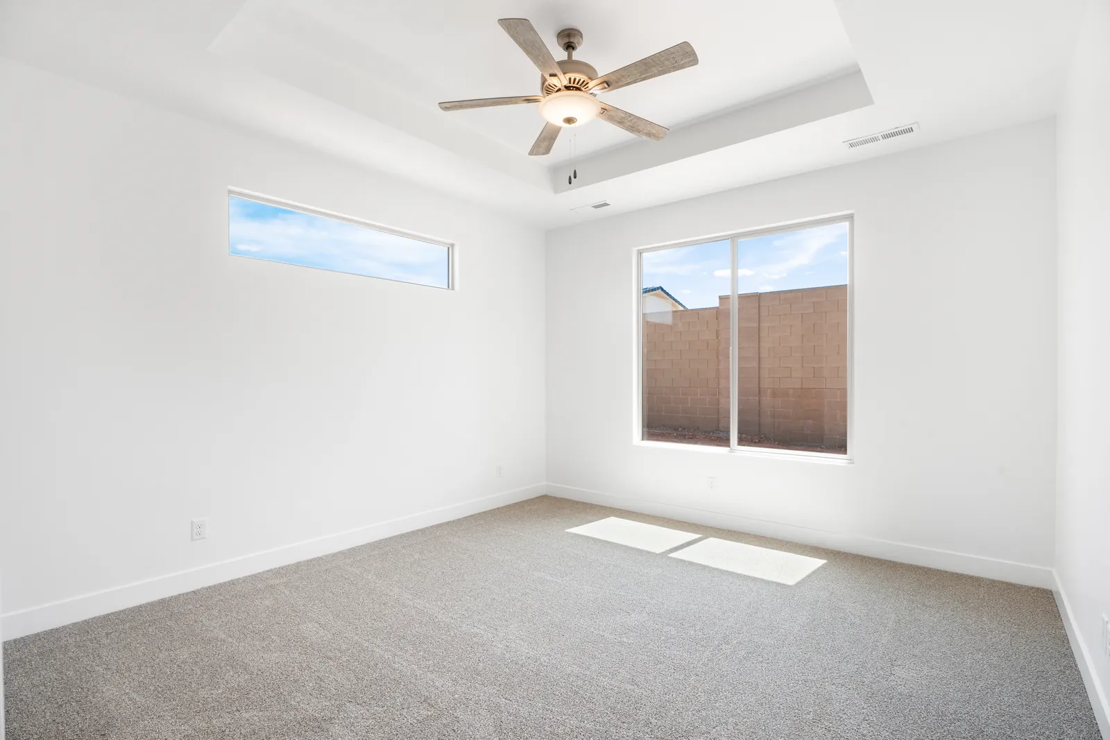 Primary bedroom with a ceiling fan and two windows